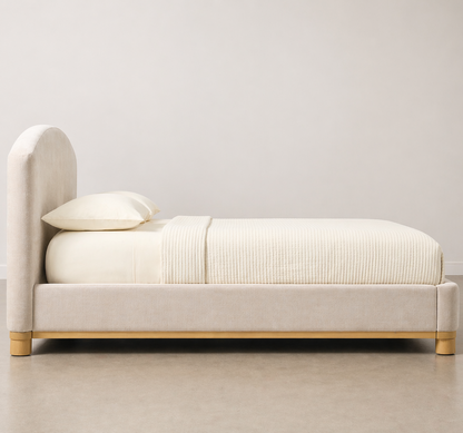 Beige bed with white bedding against a plain wall
