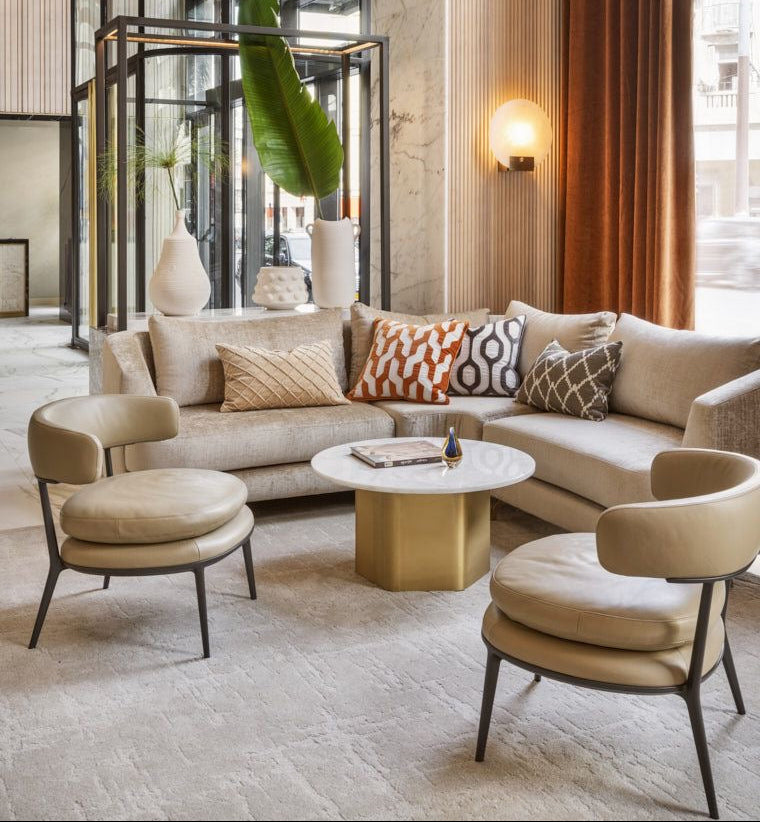 Modern living room with beige sofa, armchairs, and a coffee table in a stylish interior setting. Four businesses and hotels